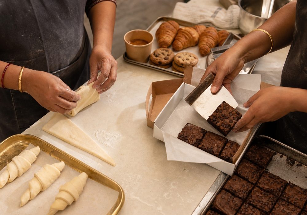 Bakery team shaping croissants and packing brownies by hand